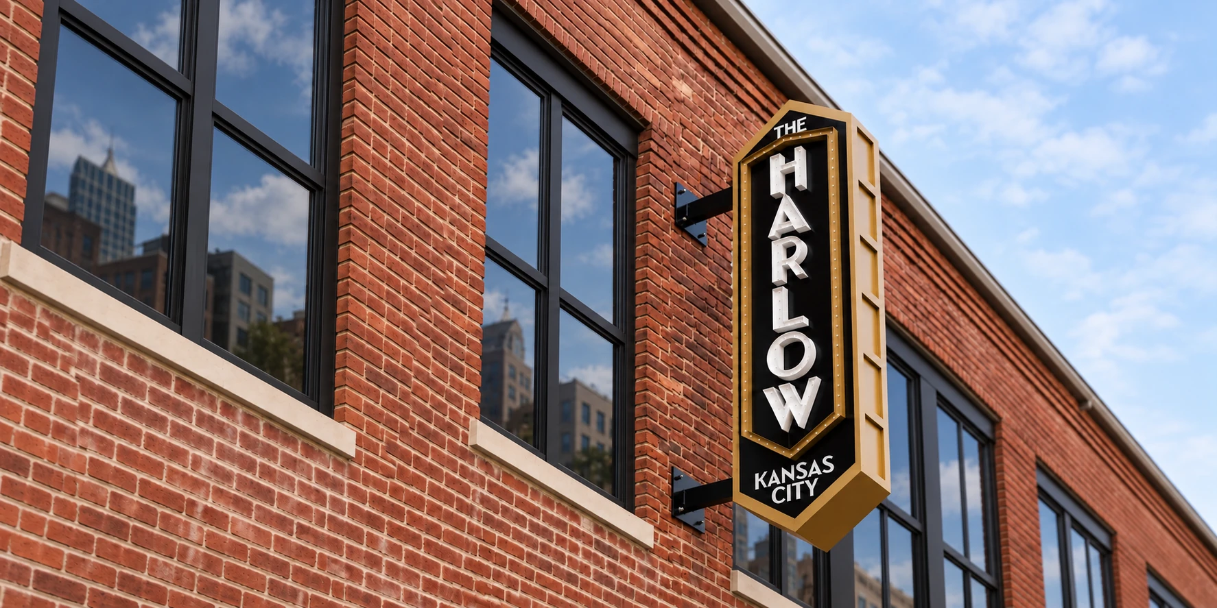The Harlow custom gold and black blade sign on its brick Kansas City building