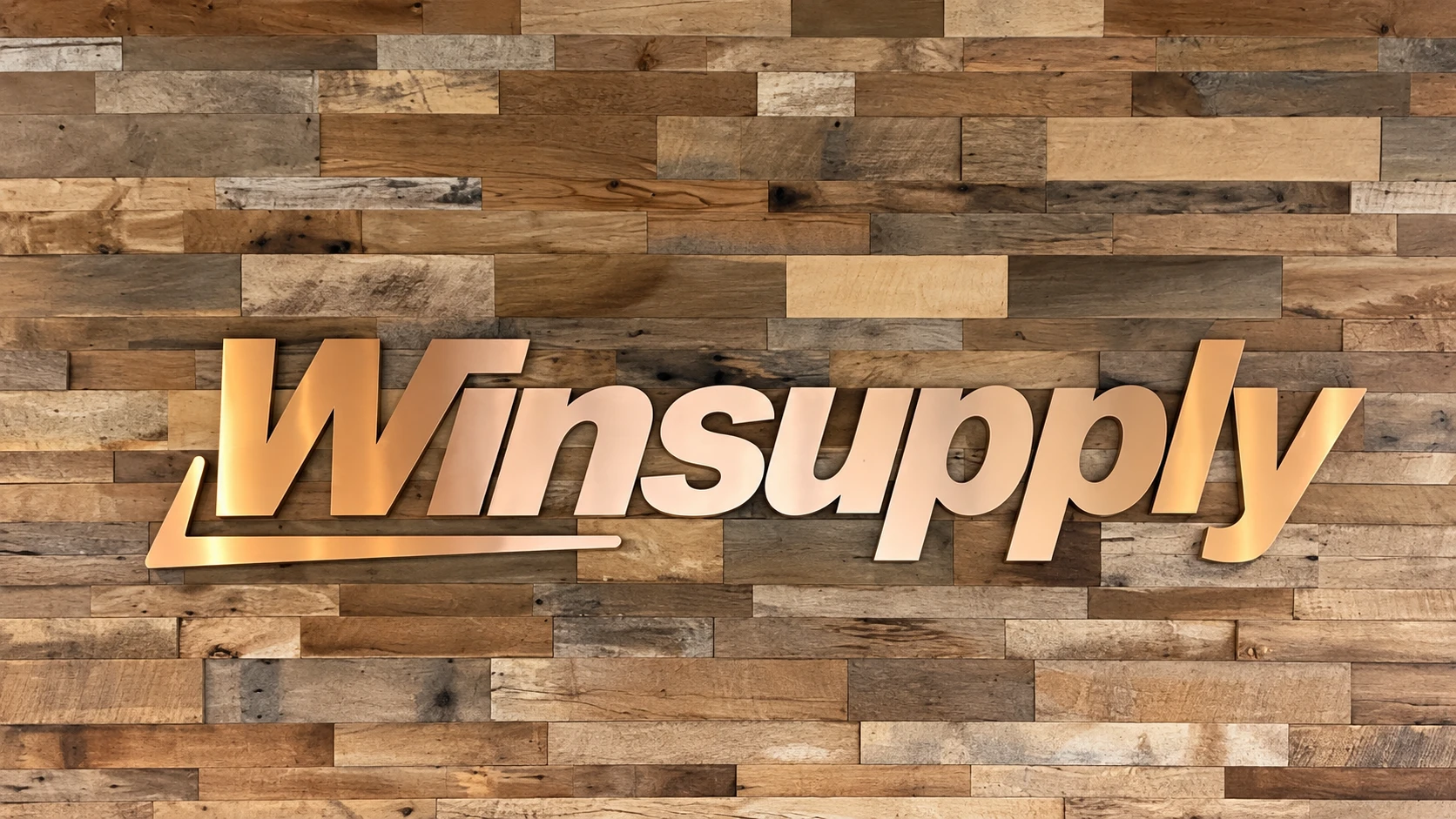 Brushed-copper laminate lettering on the Winsupply reception wall