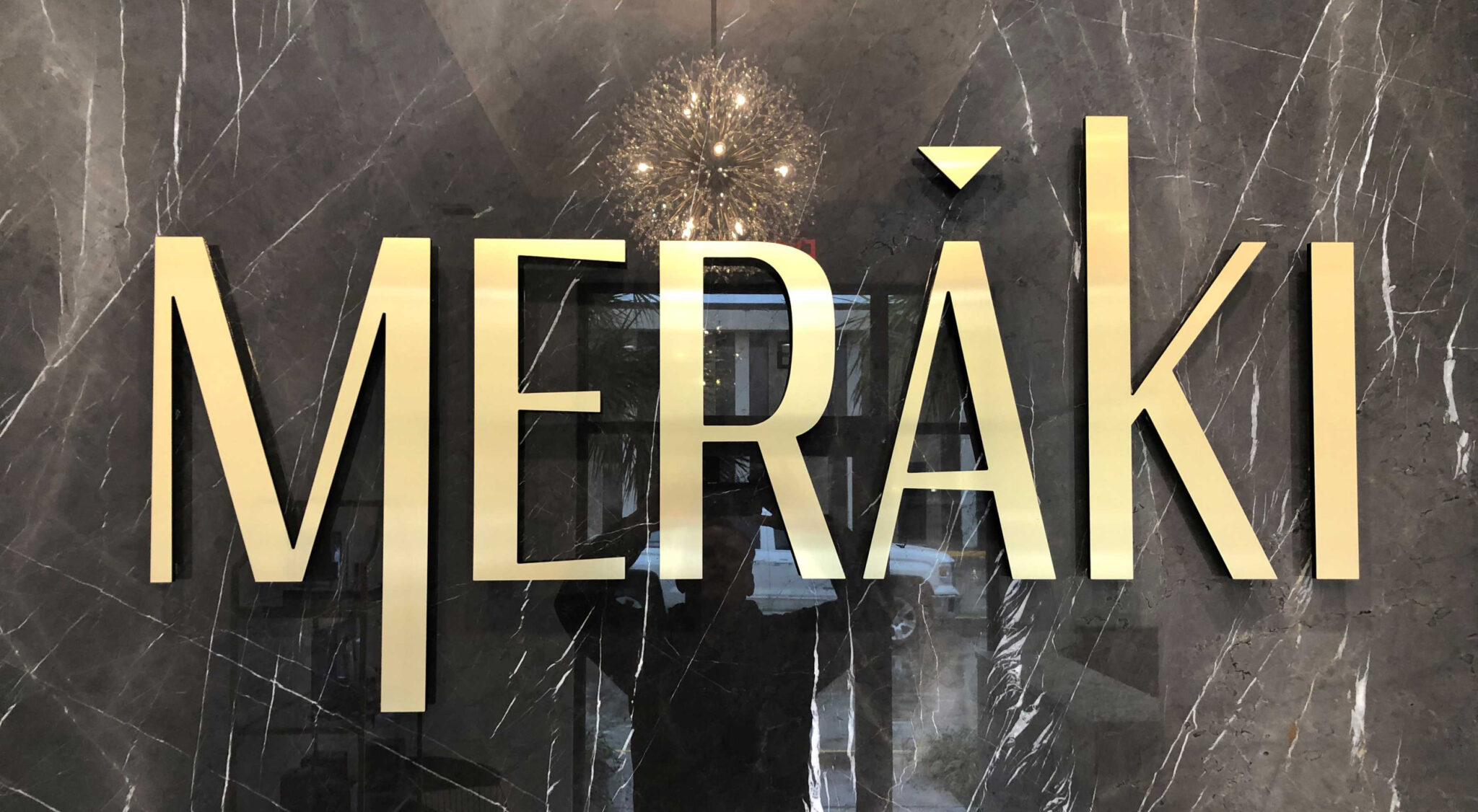 Gold GemLeaf acrylic lettering on a dark stone reception wall